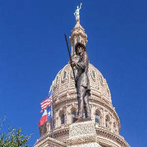 Statue of Davy Crockett with his rifle and the Texas Flag